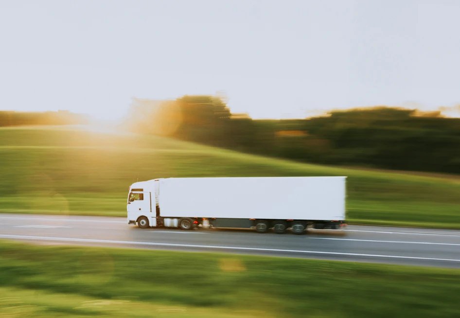 White truck on a highway at sunset, illustrating the shift of cold-chain logistics towards green and circular investment.