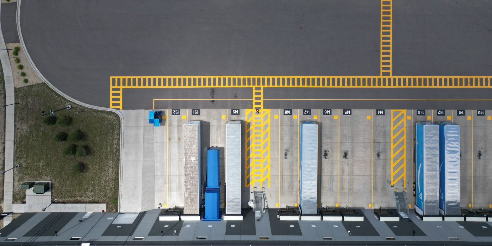 Vue aérienne de quais de chargement logistiques avec des remorques à quai, illustrant un transport maîtrisé et documenté pour les exportateurs.