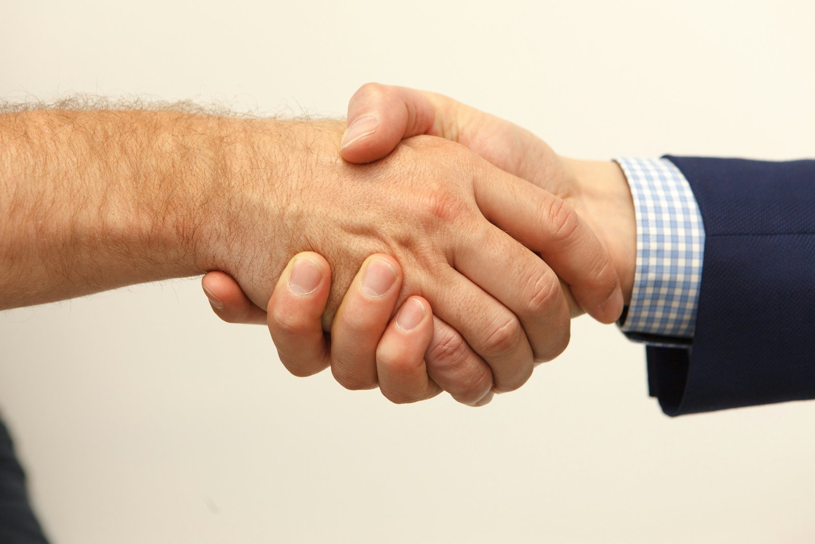 Close-up of two business professionals shaking hands, one in business attire with a checked shirt cuff visible, symbolising the trust and lasting partnership at the heart of every Provigood collaboration.
