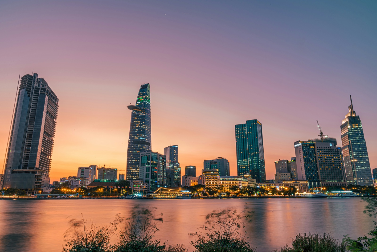 Ho Chi Minh City skyline at sunset, with the Bitexco Financial Tower reflected on the Saigon river.
