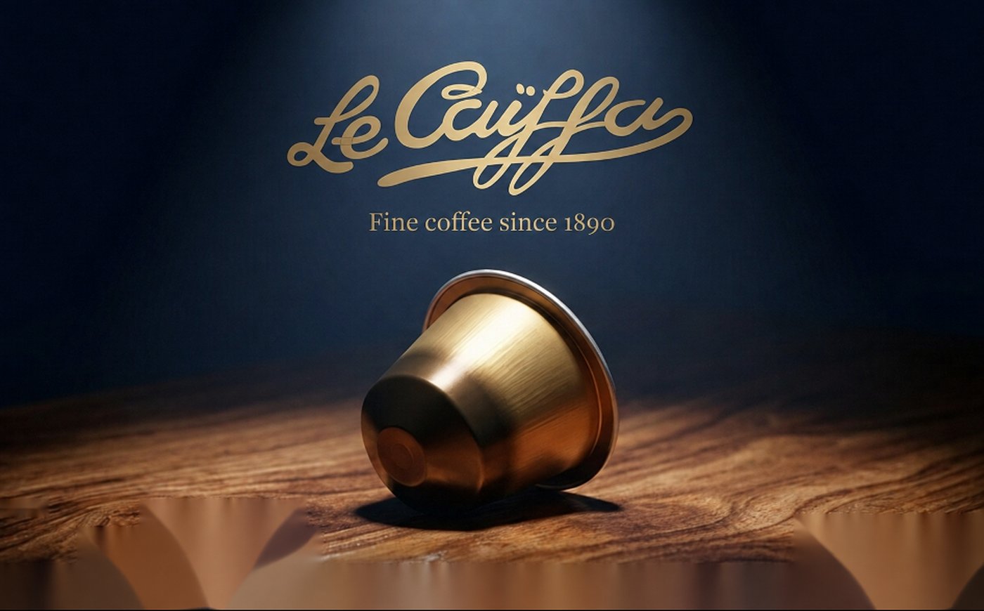 Le Caïffa gold script logo with the tagline “Fine coffee since 1890”, above a single gold coffee capsule resting on a dark wooden surface.